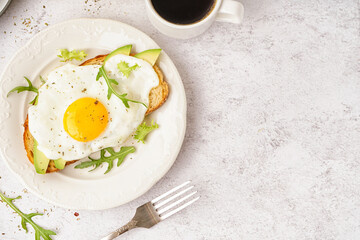 Delicious sandwich with fried egg, arugula and avocado on light background