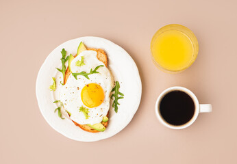 Delicious sandwich with fried egg, avocado and arugula on beige background