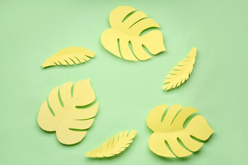 Frame made of yellow paper tropical leaves on green background