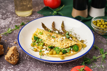 Tasty omelet with broccoli, asparagus and pea on grey background
