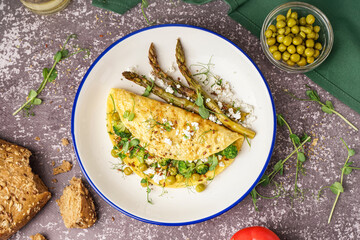 Tasty omelet with broccoli, asparagus and pea on grey background