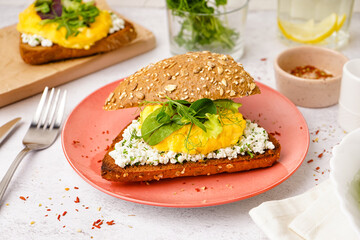 Plate with tasty scrambled eggs sandwich on light background