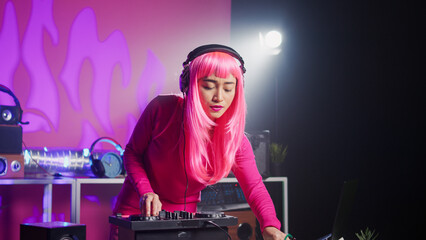 Musician standing at dj table mixing sound using professional mixer console, playing techno remix...