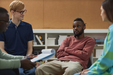 Portrait of black young man with attitude talking to therapist in support group session for troubled youth