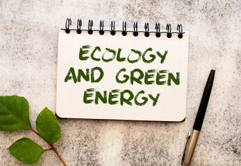 Between two sheets from a notebook on a green strip with the inscription - Ecology And Green Energy
