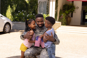 African american army soldier father embracing cute children outside house