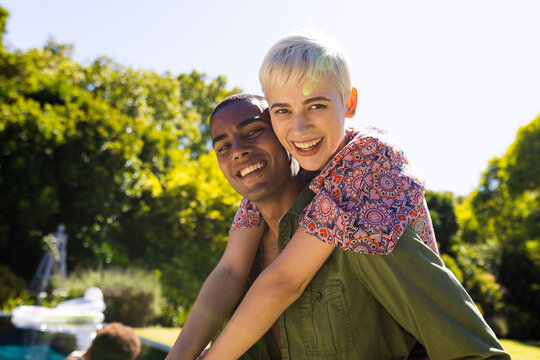 Portrait of happy diverse couple embracing and smiling in garden