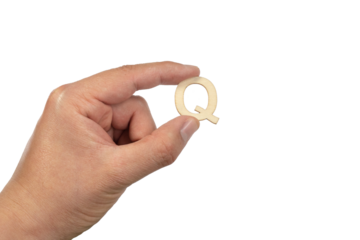 A hand holding a wooden letter q in front of a white background