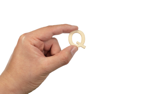 A hand holding a wooden letter q in front of a white background