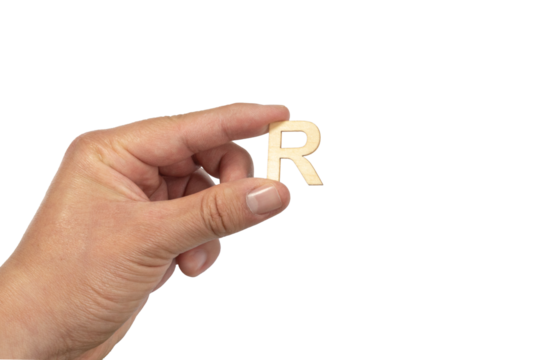 A hand holding a wooden letter r in front of a white background