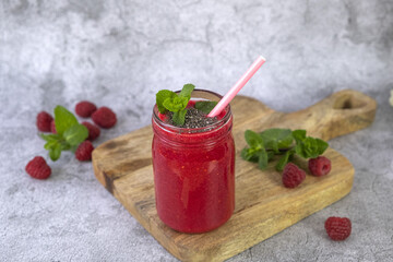 Raspberry smoothie in a jar on a gray concrete background