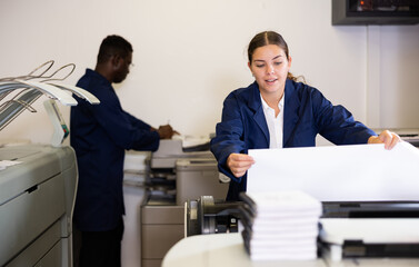 Female worker in a printing and press centar check the print quality