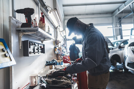 side view of an African mechanic working at the car garage, medium shot mechanic concept. High quality photo