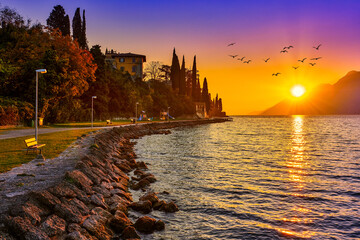 View of the beautiful Lake Garda surrounded by mountains, Scenic view of sunset at Lake Garda in the evening with the beautiful sunset colors, italy