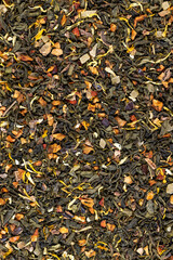 A large amount of dry green tea with pieces of fruit
