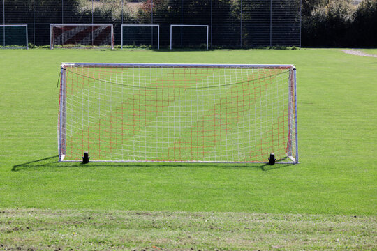 soccer goal photographed from behind on a green spring meadow without goalkeeper and players. in the background other substitute goals. during the day. sunshine