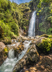 Fototapeta na wymiar Vertical shot of the beautiful hidden Mundug tropical waterfall in the Tungurahua province of Ecuador