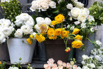 Large armfuls of pink roses, yellow and white ranunculus, bluebell, freesia, daffodils in metal pails for sale