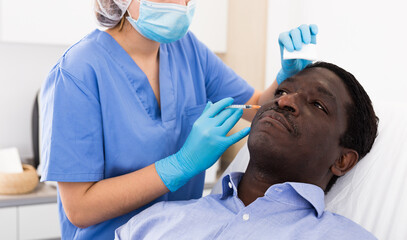 Portrait of african american male client of aesthetic cosmetology clinic during procedure of face mesotherapy. Male skin care concept