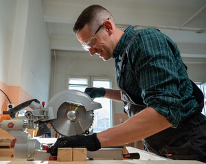 Master cuts the board with a circular saw in the workshop. 