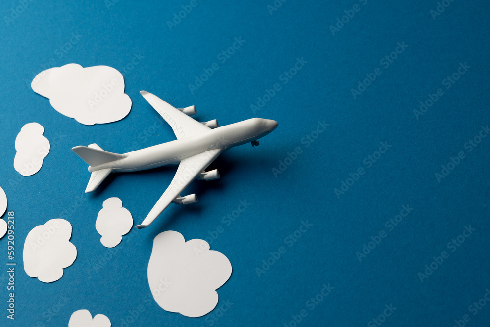 Poster close up of airplane model with clouds on blue background with copy space