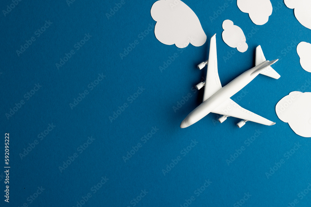 Poster close up of airplane model with clouds on blue background with copy space