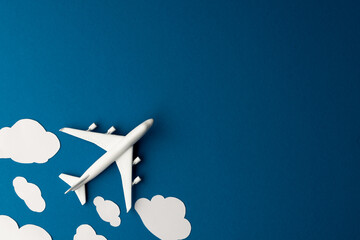 Close up of airplane model with clouds on blue background with copy space - obrazy, fototapety, plakaty