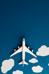 Close up of airplane model with clouds on blue background with copy space
