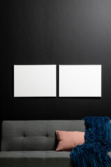 Vertical of empty white canvases with copy space and couch on black wall
