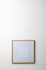 Vertical of empty wooden frame with copy space on white wall