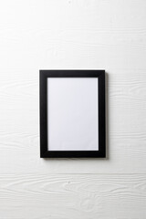 Vertical of black empty frame with copy space on white wall