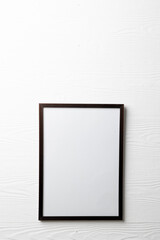 Vertical of empty dark wooden frame with copy space on white wall
