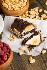 Sliced sweet cake with banana, chocolate glaze, milk filling and peanuts