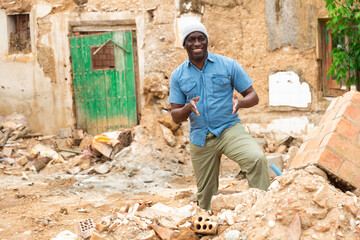 Happy smiling afro american male posing at the yard of old ruined farmhouse in a summer day