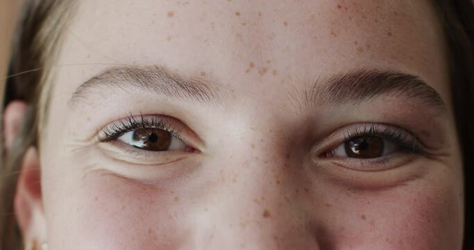 Portrait close up of the eyes of happy caucasian teenage girl with freckles smiling in slow motion
