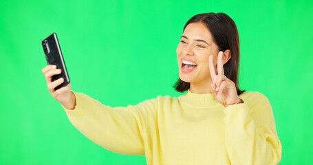 Happy woman, face and selfie on green screen with peace sign and facial expressions against studio background. Silly or goofy female model smiling for photo, emoji or memory with smartphone on mockup
