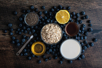 Blueberry Chia Oatmeal Ingredients on a Wood Table: Old-fashioned oats, fresh blueberries, honey, and other ingredients