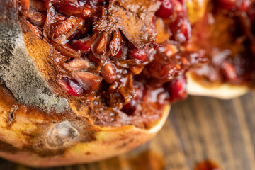 Rotten spoiled red ripe pomegranate on the board