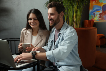 Couple with coffee and laptop spending time together in cafe