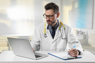 Pediatrician consulting patient online at table in clinic