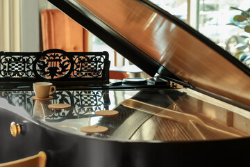 Cup and coasters on black grand piano in cafe