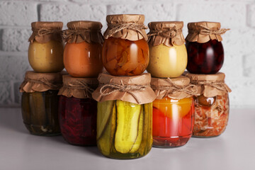 Many glass jars with different preserved products on light grey table