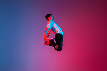Fototapeta na wymiar guy acrobat doing back fat in new lighting, male dancer jumps and falls in the air on red blue background