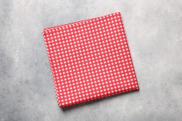 Red checkered tablecloth on light gray textured table, top view
