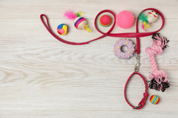Flat lay composition with pet leash and toys on white wooden background, space for text