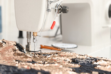 Sewing machine and beautiful fabric with paillettes indoors, closeup