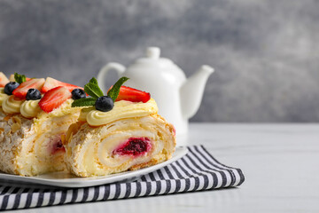 Tasty meringue roll with jam, cream, strawberry, blueberry and mint on white table, closeup. Space for text