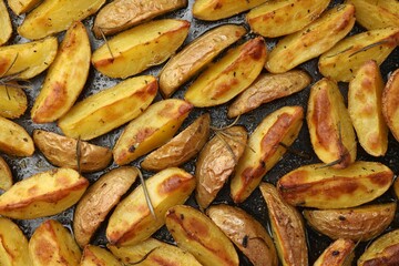 Delicious baked potatoes with rosemary on black surface, flat lay