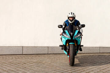 guy motorcyclist in professional protective equipment and helmet sits on sports motorcycle against...