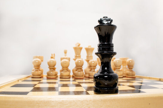 Black chess king alone against white pieces in the background. on white background